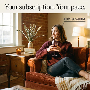 Woman sitting on a couch holding a glass of wine in a cozy living room.