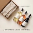 Three wine bottles from Gold Hill Winery on a beige surface with a cardboard box.