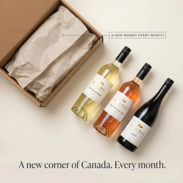 Three wine bottles from Gold Hill Winery on a beige surface with a cardboard box.